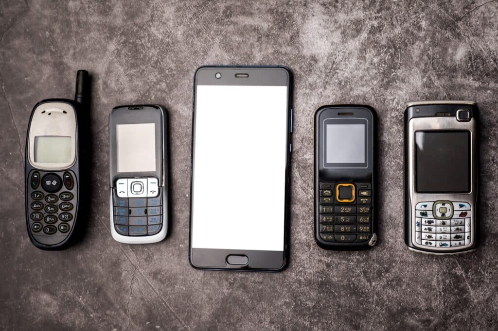 Many obsoleted cellphones and a smartphone on a grunge background.