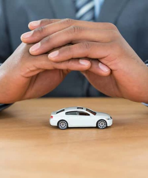 businessman-protecting-toy-car-with-hands-GQVUDT8